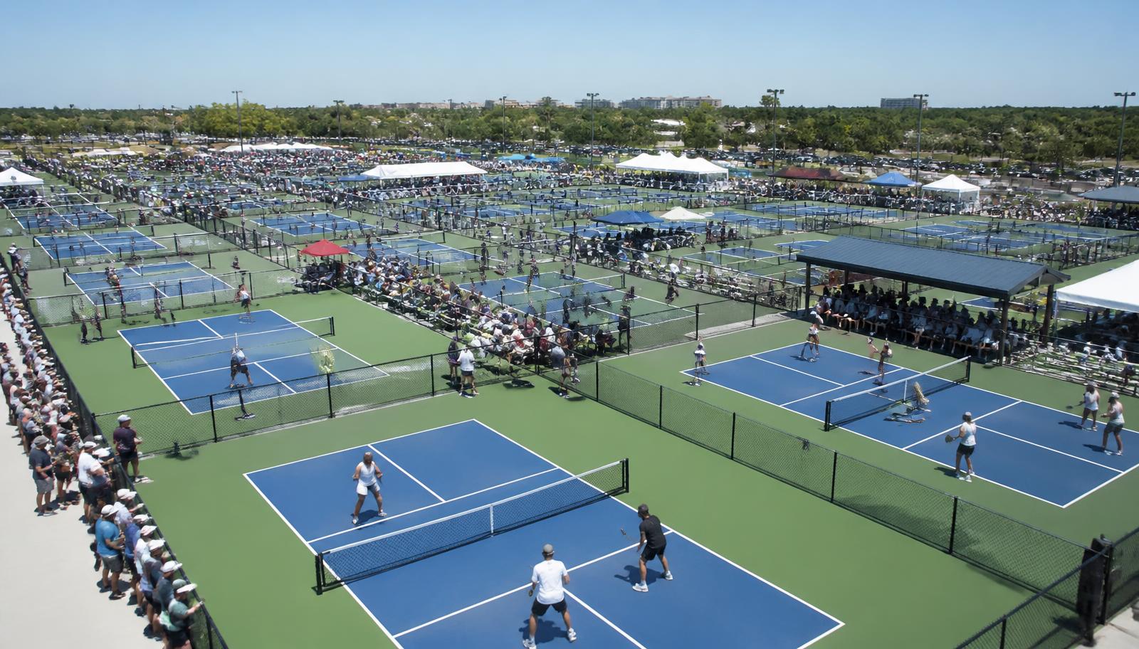 Large national pickleball tournament with players competing across multiple courts